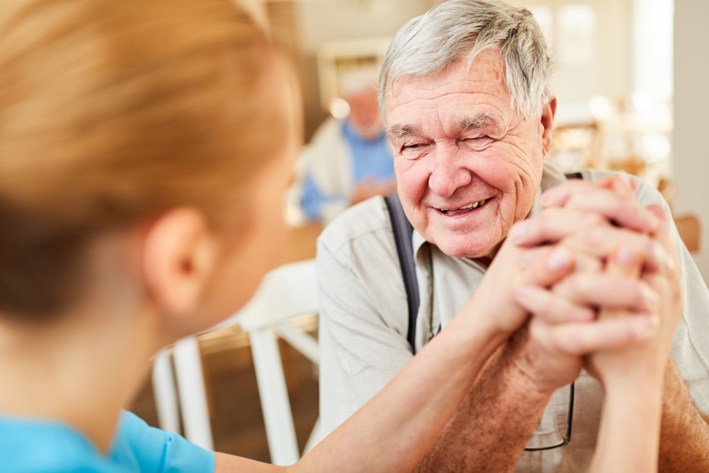 senior holding hands of caregiver