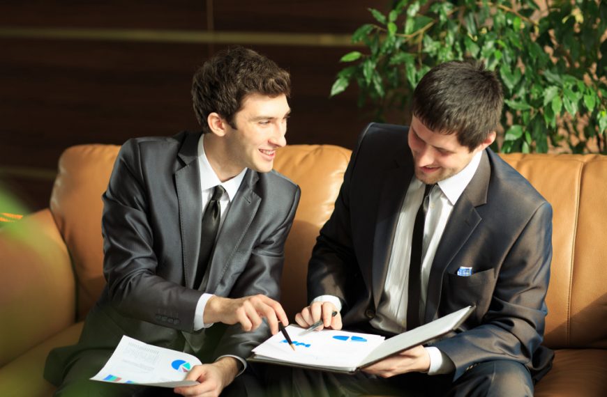 Image of two young businessmen discussing project at meeting